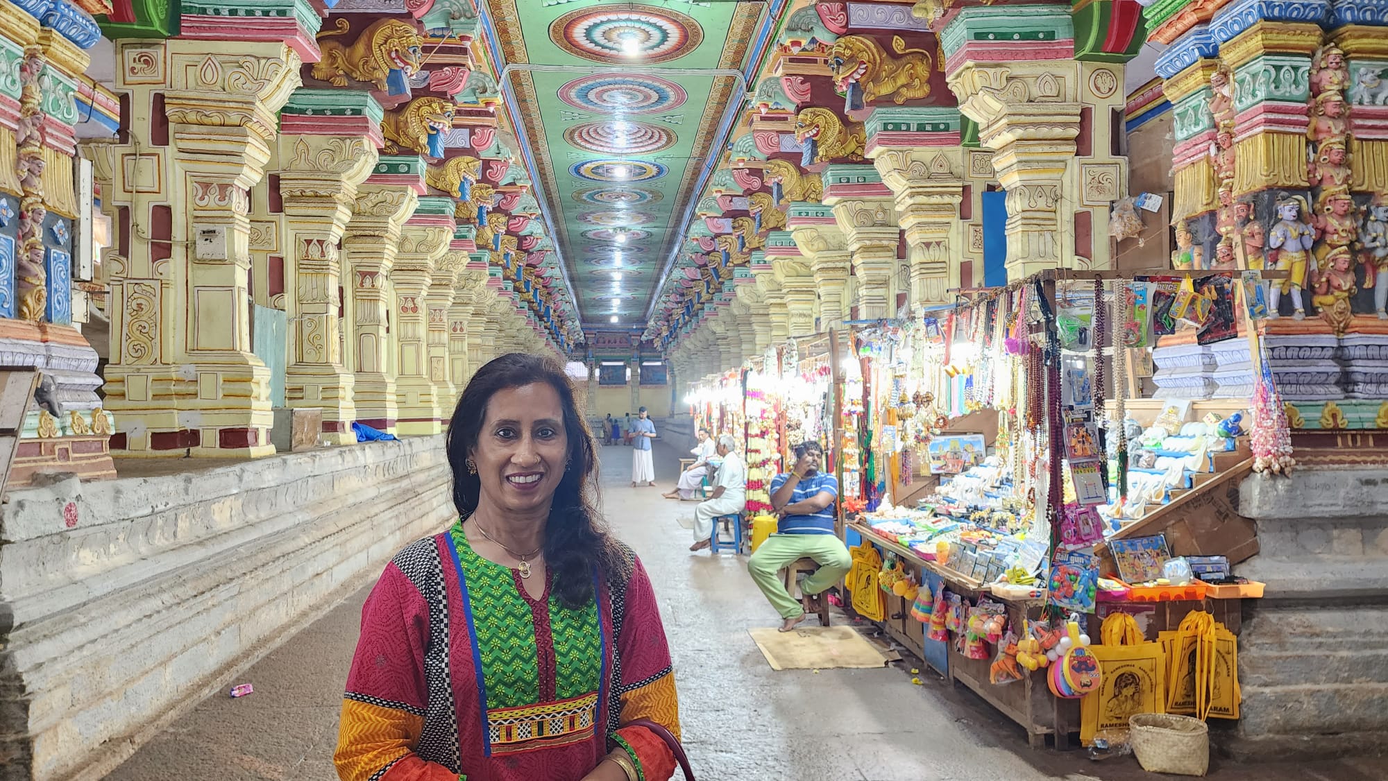 Anuradha Gupta, Hindi teacher at Sheila's Hindi Classes, greeting with namaste in front of an Indian temple